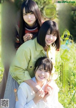 A group of young women sitting on top of a lush green field.