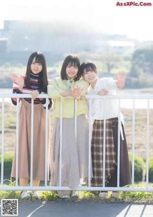 A group of three young women posing for a picture in a field.