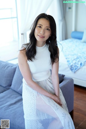 A naked asian woman sitting on a wooden floor.