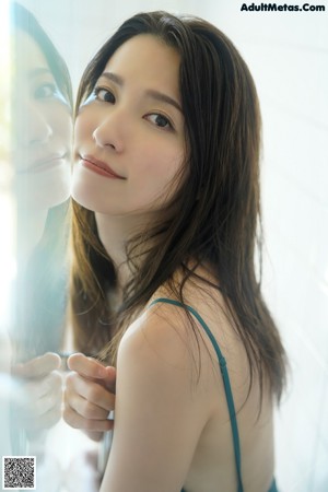 A woman in a white towel standing in a bathroom.