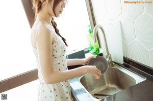 A woman in a white dress holding a bowl of food.