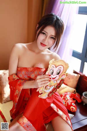 A woman in a red lingerie sitting on a bed.