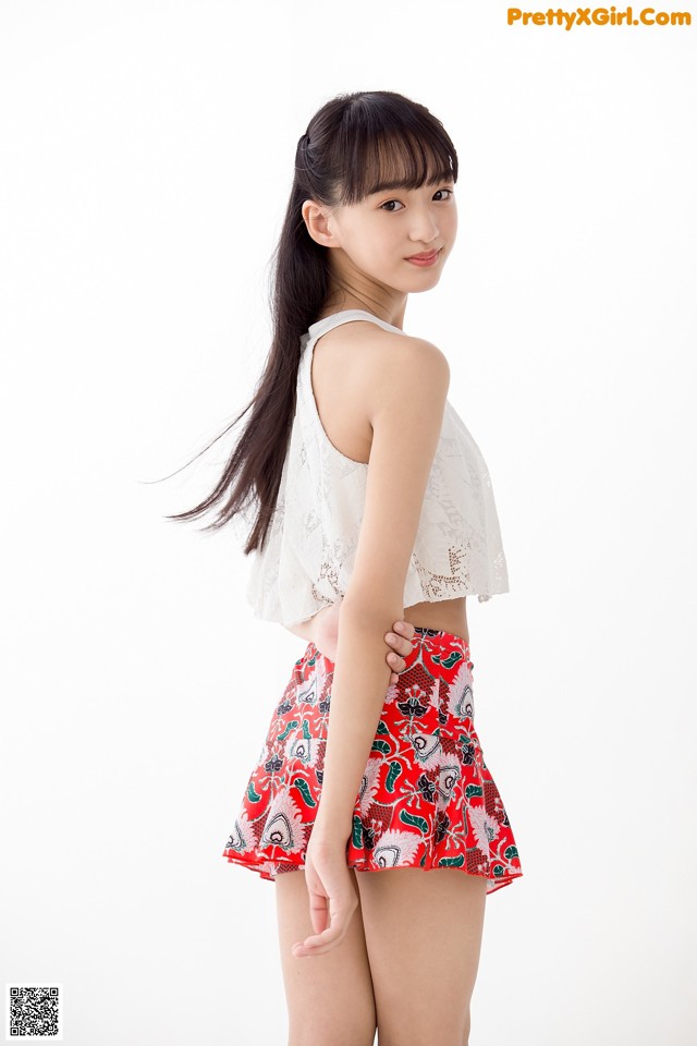 A woman in a white top and red skirt posing for a picture.