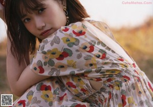 A young girl in a red cardigan standing in the leaves.