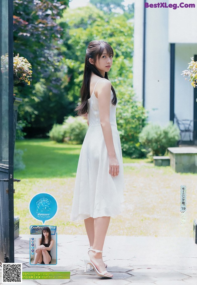 A woman in a white dress standing in front of a door.