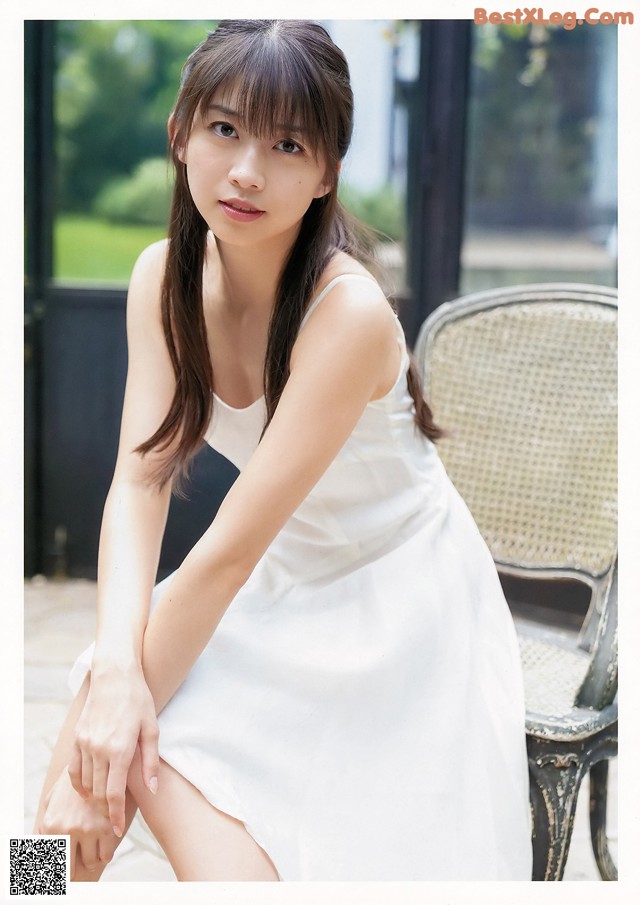 A woman in a white dress sitting on a chair.