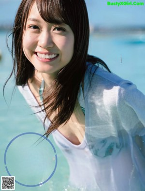 A woman sitting on the beach with her back to the camera.