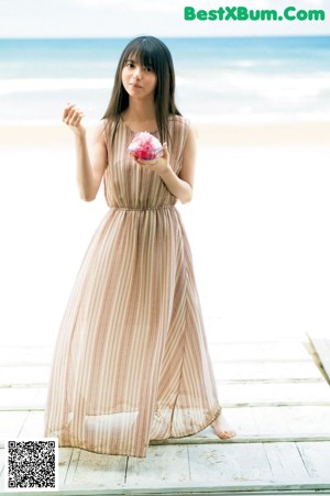 A woman with long black hair standing on a beach.