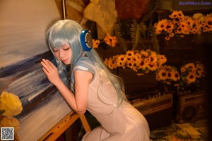 A woman with long blue hair holding a bunch of flowers.