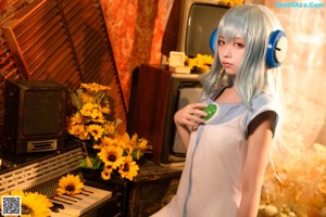 A woman with blue hair sitting on the floor holding a sunflower.
