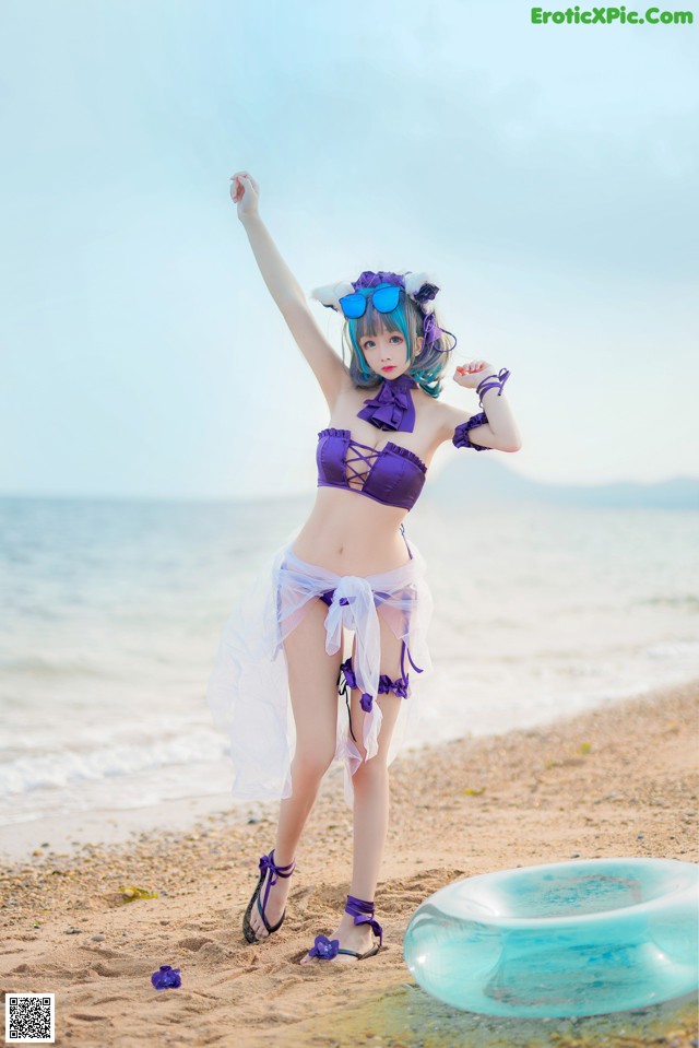 A woman in a purple bikini standing on a beach.