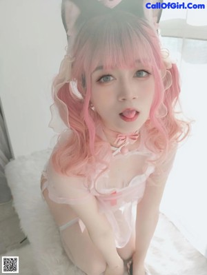 A woman in a pink and white outfit is posing for a picture.