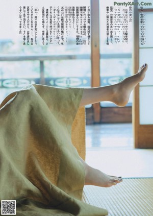 A woman looking out of a window with her hand on her chin.