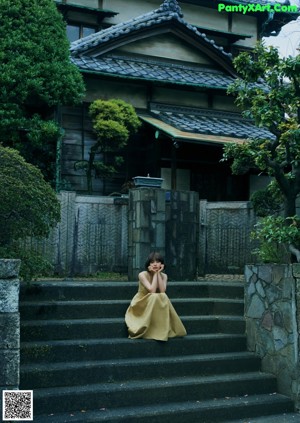 A woman's bare feet sitting on a bed in front of a window.