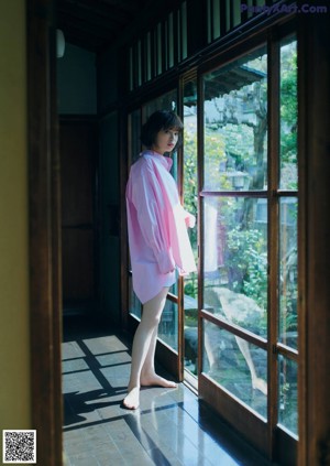 A woman's bare feet sitting on a bed in front of a window.