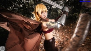 A woman in a red bikini holding a sword in the woods.