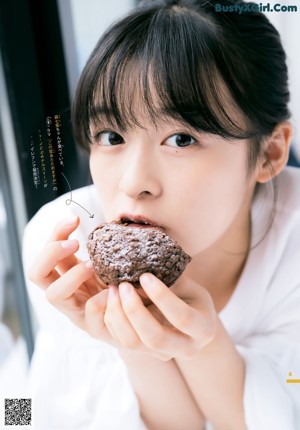 A young girl leaning against a wall with her hand on her chin.