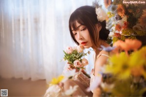 A woman sitting on the floor in front of a bunch of flowers.