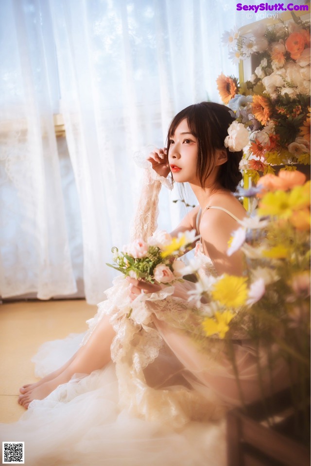 A woman sitting on the floor holding a bouquet of flowers.