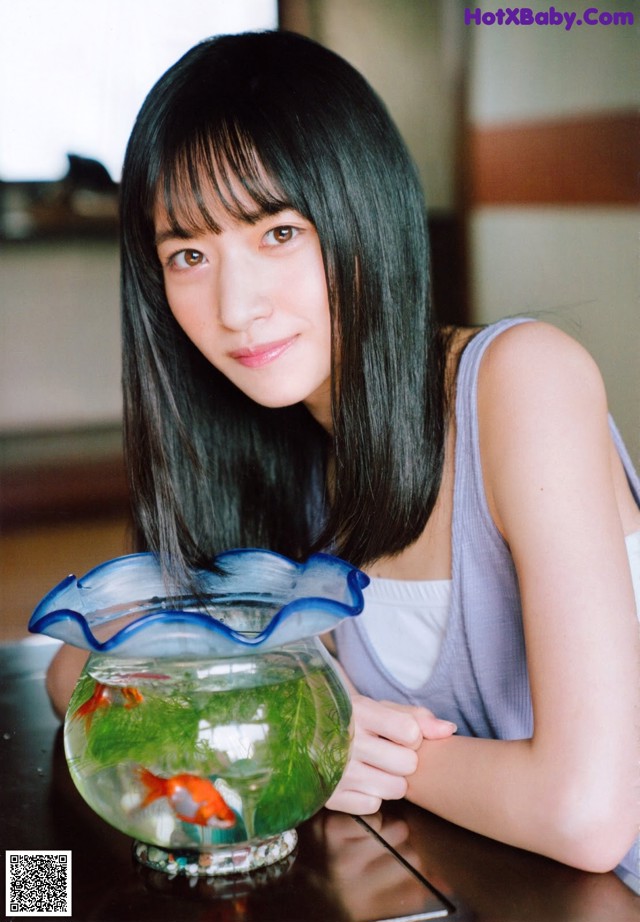 A woman sitting at a table with a fish bowl.