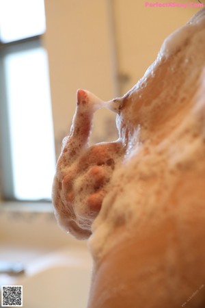 A woman wrapped in a white towel in a bathroom.