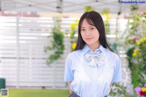 A young woman in a school uniform sitting on the grass.
