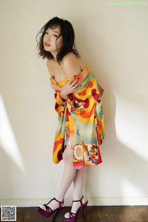 A woman sitting on the floor in a colorful dress.