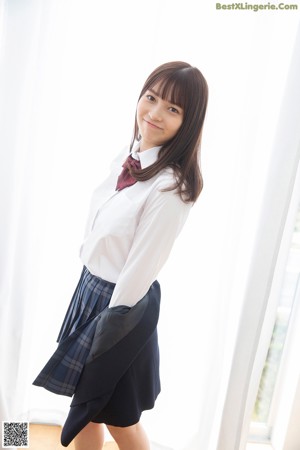 A young woman in a school uniform leaning against a door.