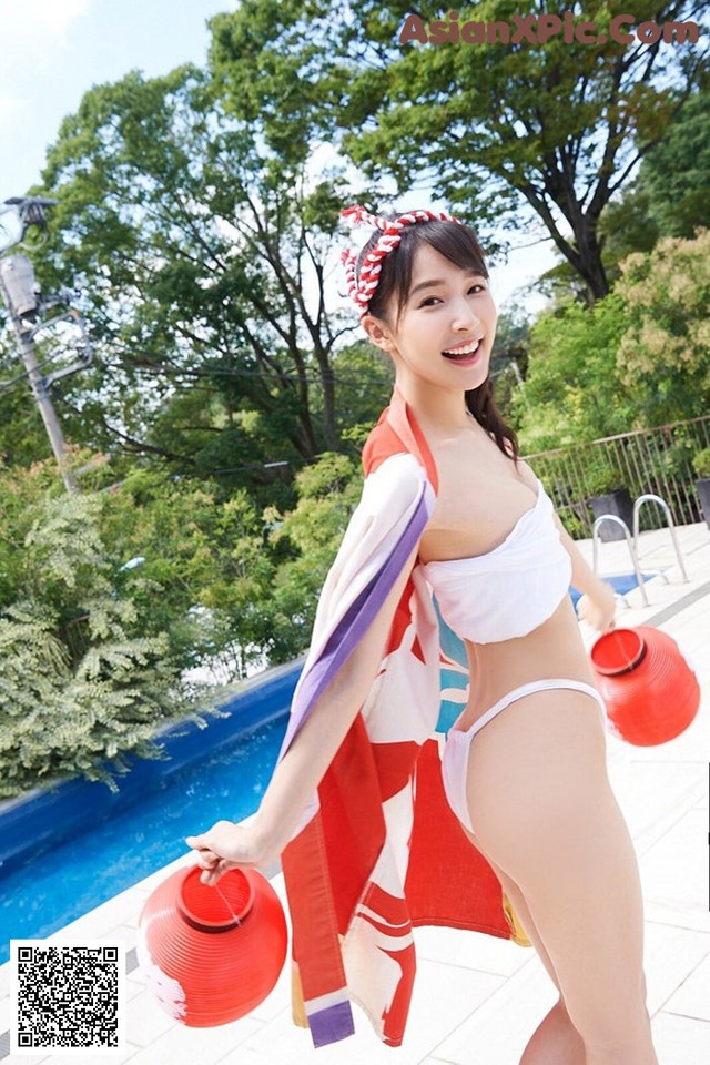 A woman in a white bikini holding a red lantern.