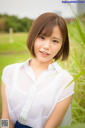 A woman in a blue shirt is posing for the camera.