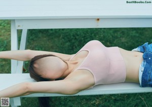 A woman laying on a couch wearing a black top and gray shorts.