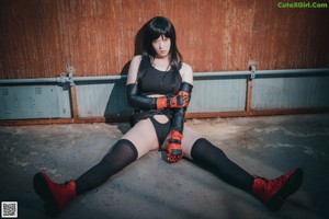 A woman in a black leather outfit crouching down on the ground.