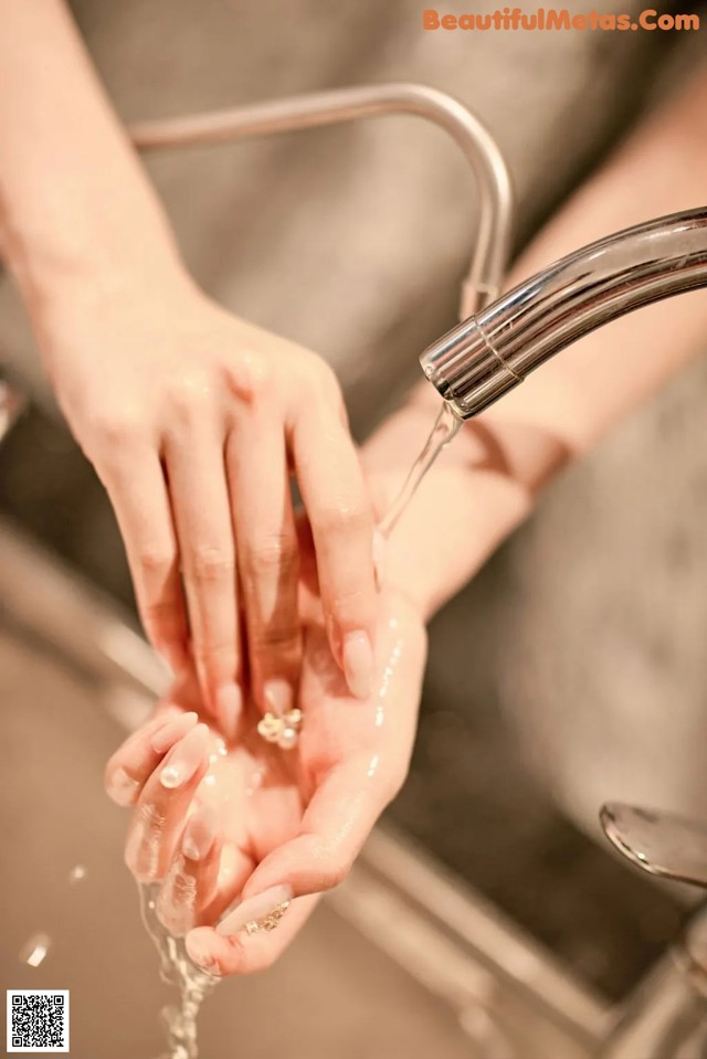 A woman washing her hands under a faucet. 