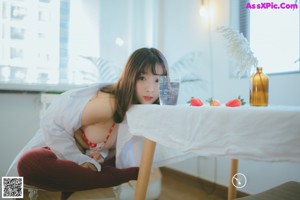 A woman in a white shirt and red stockings sitting on the floor.