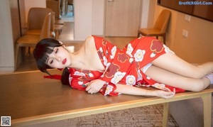 A woman in a red kimono sitting on a table.