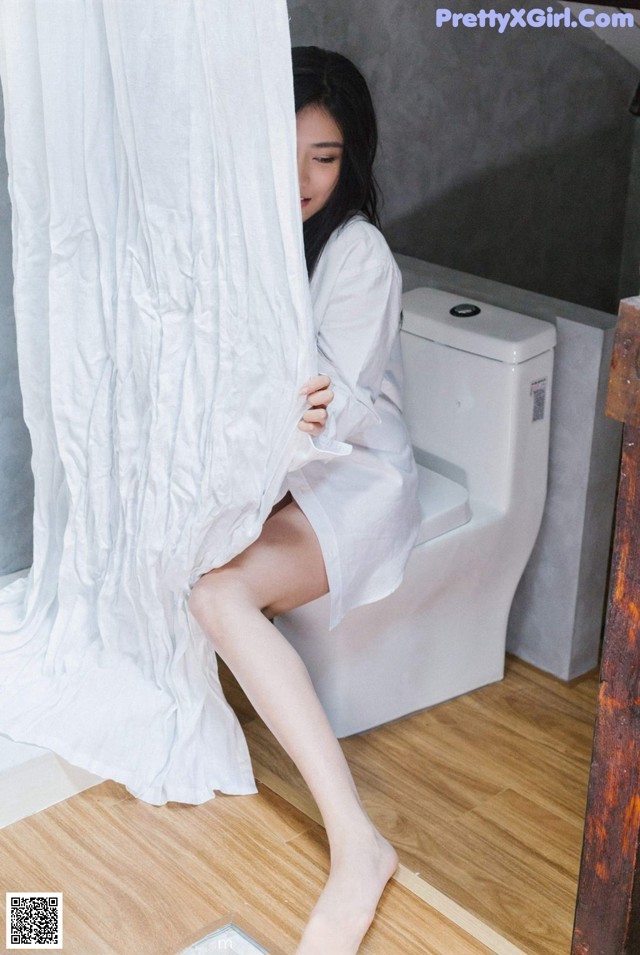 A woman sitting on a toilet in a bathroom.