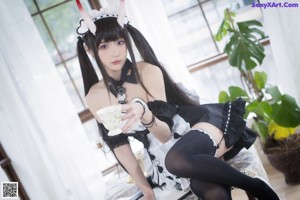 A woman in a black and white dress sitting on a table.