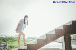 A woman in a white shirt is standing on some stairs.