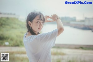 A woman in a white shirt and blue shorts posing for a picture.