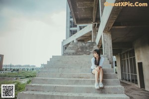 A woman in a white shirt is standing on some stairs.