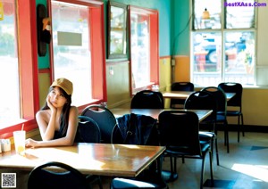 A woman sitting at a table with a drink in her hand.