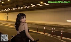 A woman in a black dress standing in a tunnel.