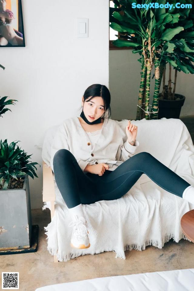 A woman sitting on a white couch in a living room.