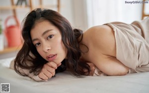 A naked asian woman laying on a bed in lingerie.