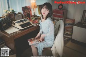 A woman sitting at a desk holding a book.