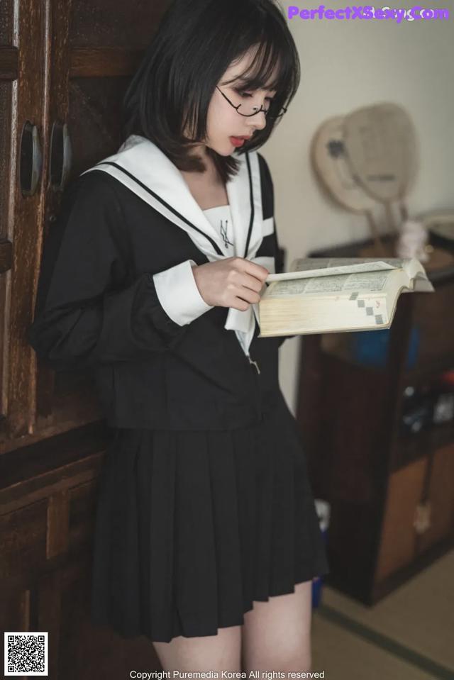 A woman in a school uniform is reading a book.