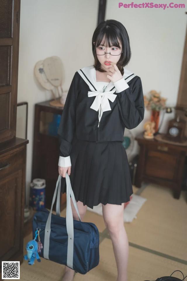 A woman in a school uniform holding a blue bag.