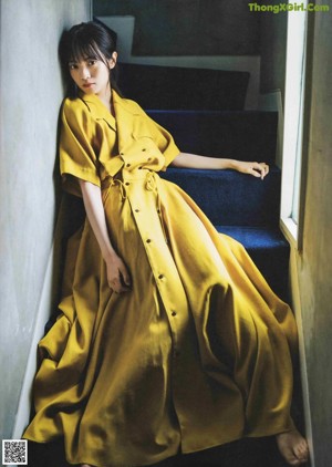 A woman in a yellow dress sitting on a chair.