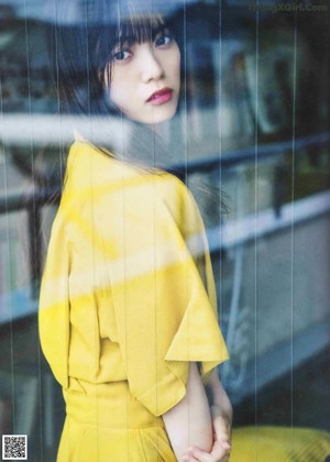 A woman in a yellow dress sitting on the stairs.