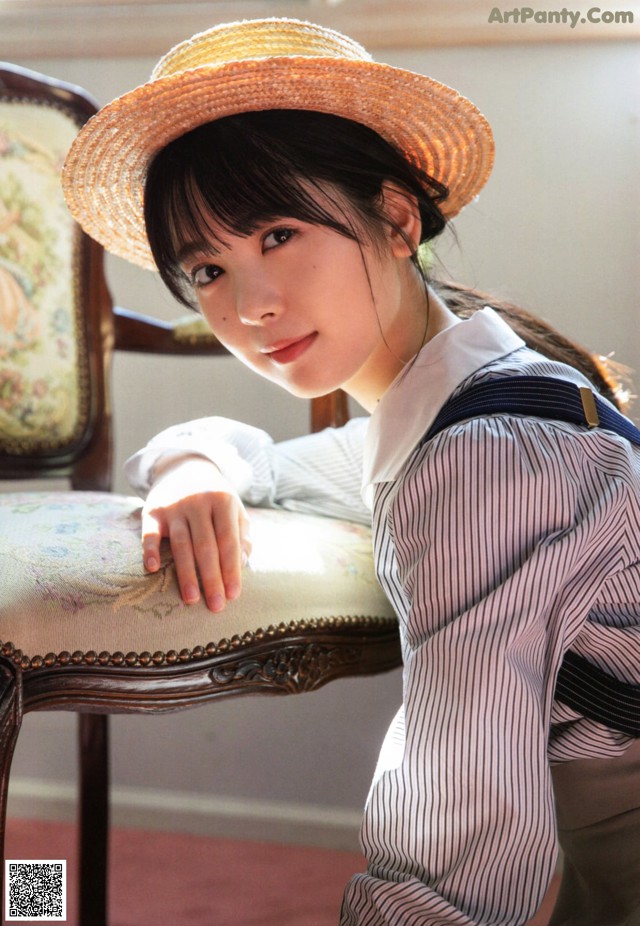 A woman in a straw hat sitting on a chair.